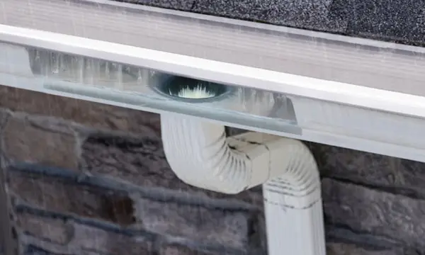 Gutter guard letting rainwater flow into a seamless gutter and downspout on a Virginia Beach home