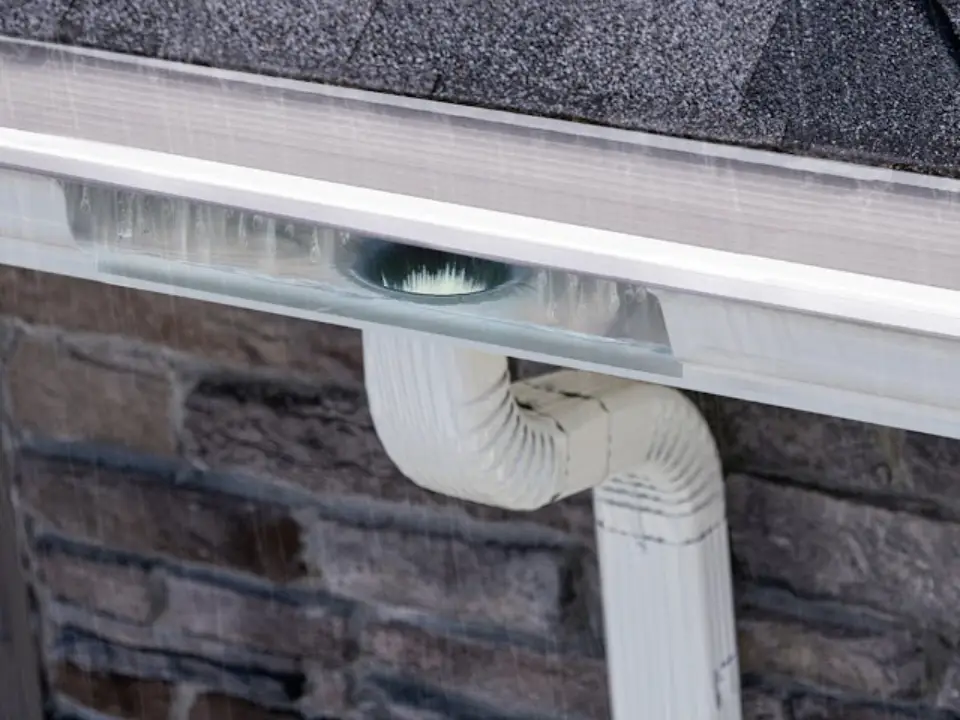 Gutter guard letting rainwater flow into a seamless gutter and downspout on a Virginia Beach home